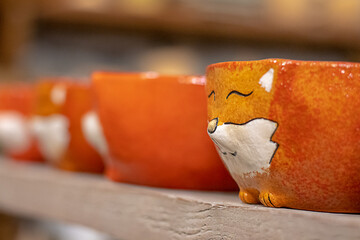 Clay ceramic cups in the shape of red fox faces. Selective focus.