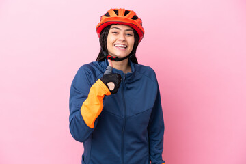 Teenager cyclist girl isolated on pink background giving a thumbs up gesture