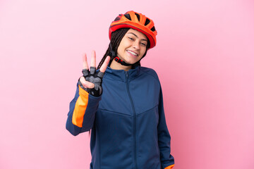 Teenager cyclist girl isolated on pink background happy and counting three with fingers