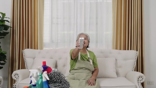 Handheld Shot Footage, Housekeeper wearing an apron to clean the house She was tired and hot, so she turned on the air conditioning to cool down in the living room.