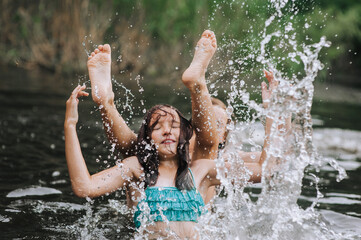 Fototapeta premium Two girlfriends, children in water playing, laughing, having fun in the lake in summer, swimming in the sea on vacation. Photography, portrait, childhood concept.