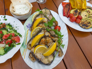 Grilled steaks of sturgeon on plate, fresh and baked vegetables
