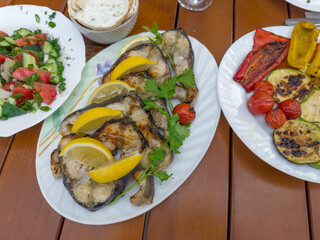 Grilled steaks of sturgeon on plate, fresh and baked vegetables