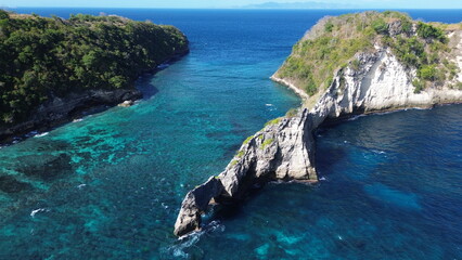 Fototapeta premium The image showcases a stunning coastal landscape with a turquoise sea, rocky cliffs, and lush greenery. It captures the beauty of nature and the serenity of the ocean.