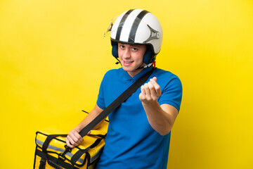 Young Brazilian man with thermal backpack isolated on yellow background making money gesture