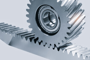 A gear is shown with a ball bearing in the center. The gear is part of a machine and is turning. ndustrial background concept