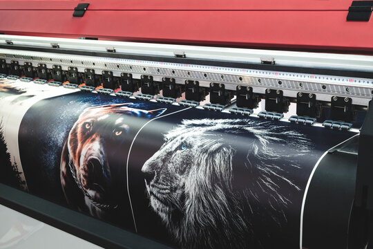 A large printer is printing a series of images, including a dog and a lion. The printer is black and red, and the images are colorful and detailed. modern technology concept background
