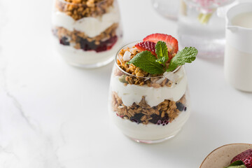 Yogurt with crispy granola, berries and mint leaves for a delicious breakfast. Copy space