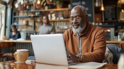A middle aged African American man using a laptop in a coffee shop.