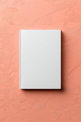 Minimalistic white hardcover book on a peach textured background. Ideal for concepts featuring design, literature, education, and minimalism.