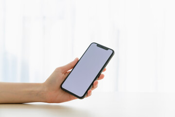 Hand holding smartphone mockup of blank screen for graphic display montage.