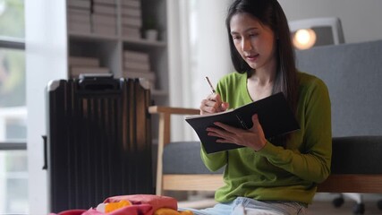 Organized woman planning travel at home, writing in notebook