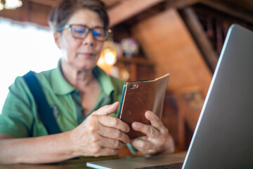 Senior asian women use smartphone with laptop sitting in coffee shop