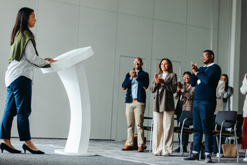 Female leader giving a business presentation at a conference event, receiving applause from the...