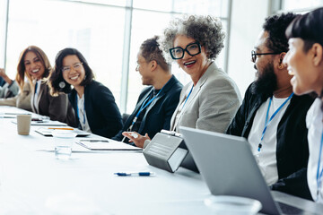 Diverse colleagues laughing and engaging in a corporate meeting in a bright office environment