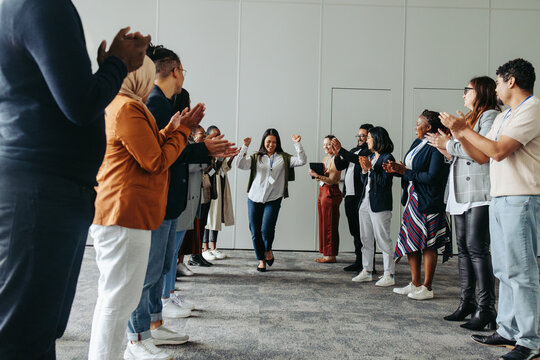 Diverse group of business professionals applauding and celebrating a woman in a corporate setting