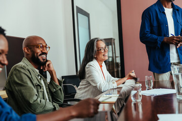Happy colleagues laughing in a modern boardroom during a casual office meeting