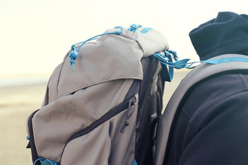 A person wears a backpack with straps in nature