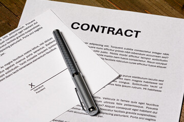 Paper contract form with a signature about to be signed on a signature field. 