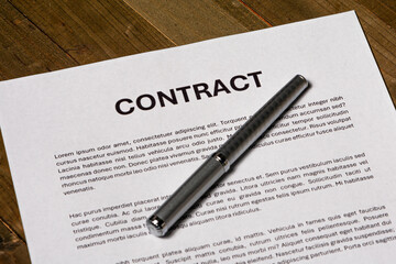 Paper contract form with a signature about to be signed on a signature field. 