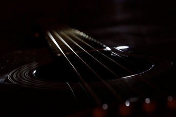 The strings of a six-string guitar shine in the dark. close-up photo in a dark key