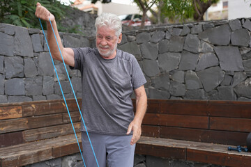 Senior man exercises with a resistance band in an outdoor setting, promoting fitness and healthy living for elderly individuals