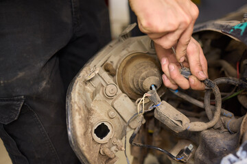 Person fixing headlight in a garage with Automotive lighting and tools
