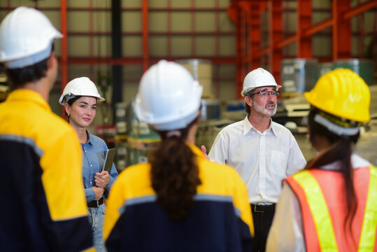 Professional Caucasian manager engineer wearing safety hardhat is training industry worker, workshop factory operator, mechanical engineering team production in heavy industrial manufacture factory.