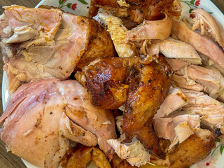 Plate full of a whole, roasted chicken cut into leg and thigh quarters, wings, and sliced breast