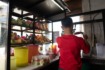 Juice seller makes orders for customers. Men preparing juices in plastic for the customer in the plastic bag. Fresh ready to serve fruits juice from Indonesia