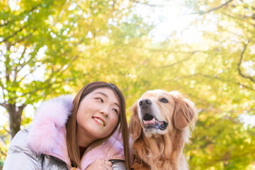 顔を見合わせているゴールデンレトリバーと飼い主の若い日本人女性