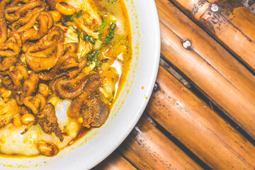 Chicken porridge bowl served with unique dishes. Traditional chicken porridge with chicken intestine satay dishes, authentic traditional from Indonesia. Macro photo of traditional food from Indonesia.