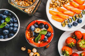 Light berry dessert with Greek yogurt and granola, parfait with fresh berries strawberries and blueberries on a gray table. Selected focus.