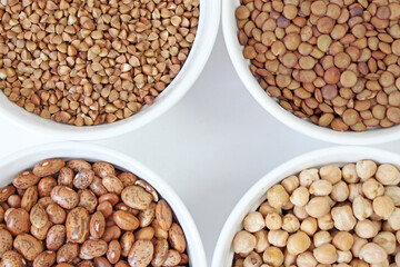 Four white bowls are filled with different types of legumes, creating a balanced and nutritious meal option
