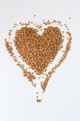 Buckwheat is forming a heart shape on a white background representing the concept of healthy eating