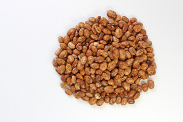 Large pile of pinto beans on a white background, showcasing their natural texture and rich brown color. Perfect for food themes with copy space