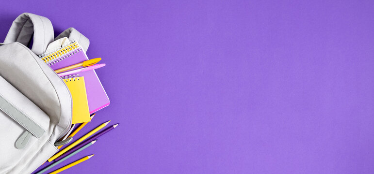 Back to school. Purple pencil case with pencils and notebooks on purple background. Office desk with copy space. Flat lay, top view