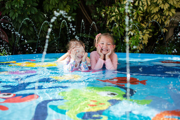Happy children in a pool. Happy childhood concept. Laughing kids enjoying summer at the splash pad © Ana