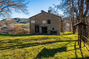 Woman with backpack admiring  the old house in the apennines. Ca Cornio, Modigliana, Forlì, Emilia Romagna, Italy, Europe.