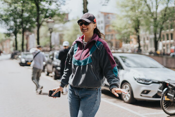Joyful woman walks through a sunny street in Amsterdam, capturing the vibrant city life. Casual attire and cheerful demeanor highlight a relaxed urban experience.