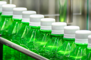 The empty green drinking bottles on the conveyor belt for filling process.