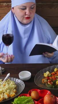 A Jewish woman in blue at the Pesach Seder table reads kiddush with a glass of wine