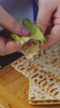 A Jewish woman in blue at a laid Pesach Seder table dips karpas in salt water