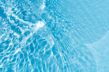 Blue water with ripples on the surface. Defocus blurred transparent blue colored clear calm water surface texture with splashes and bubbles. Water waves with shining pattern texture background.