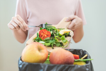 Compost from leftover food, asian young housekeeper woman hand holding cutting board use fork scraping waste, rotten vegetable throwing away into garbage, trash or bin. Environmentally responsible.