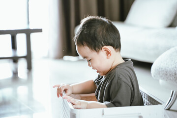 little kids boy playing in plastic boxes. children have a fun at home concept.