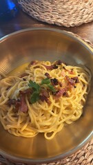 Delicious Carbonara Pasta Served in a Golden Bowl with Fresh Herbs, Crispy Bacon, and Creamy Sauce, Capturing the Essence of Authentic Italian Cuisine in a Cozy Dining Setting