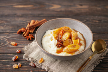 Sweet milky semolina porridge with caramelised apples and bananas in a bowl on the table. Healthy children's breakfast