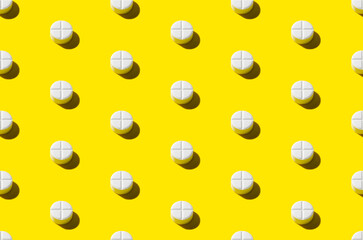 Round tablet pill pattern on a yellow background. Hard shadows.