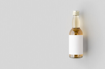 Miniature spirits, liquor bottle mockup. Clear glass, amber liquid with a blank label and copyspace.